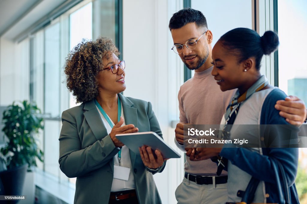 Happy multiracial couple and their financial advisor using touchpad on a meeting in the office.